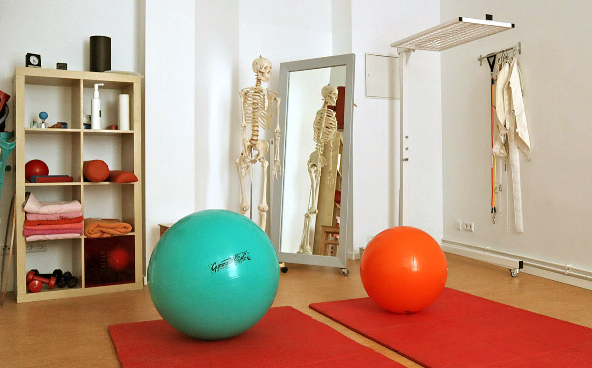 Foto von Behandlungsraum mit verschiedenen Hilfsmitteln wie Matten, Bällen und Anschauungsmaterial